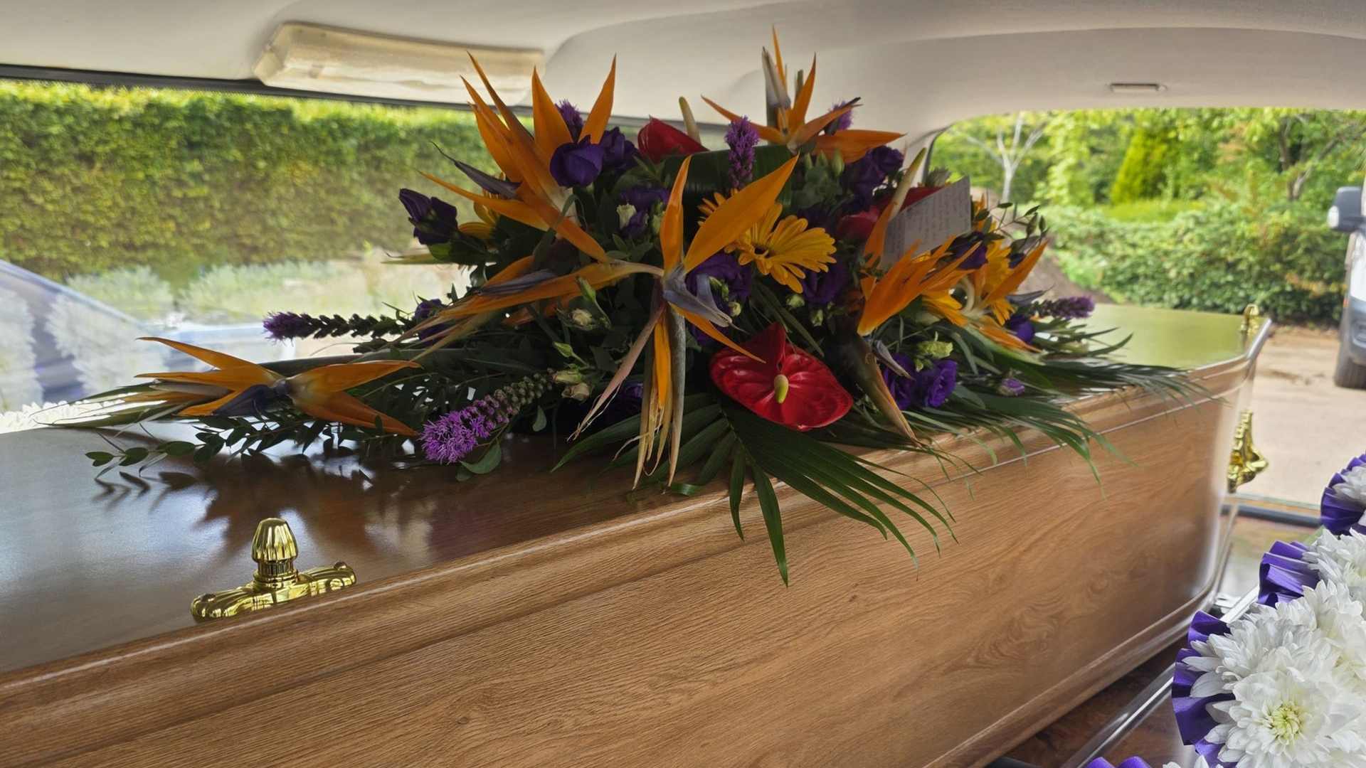 A large house with a statue in front of it is surrounded by trees and bushes.