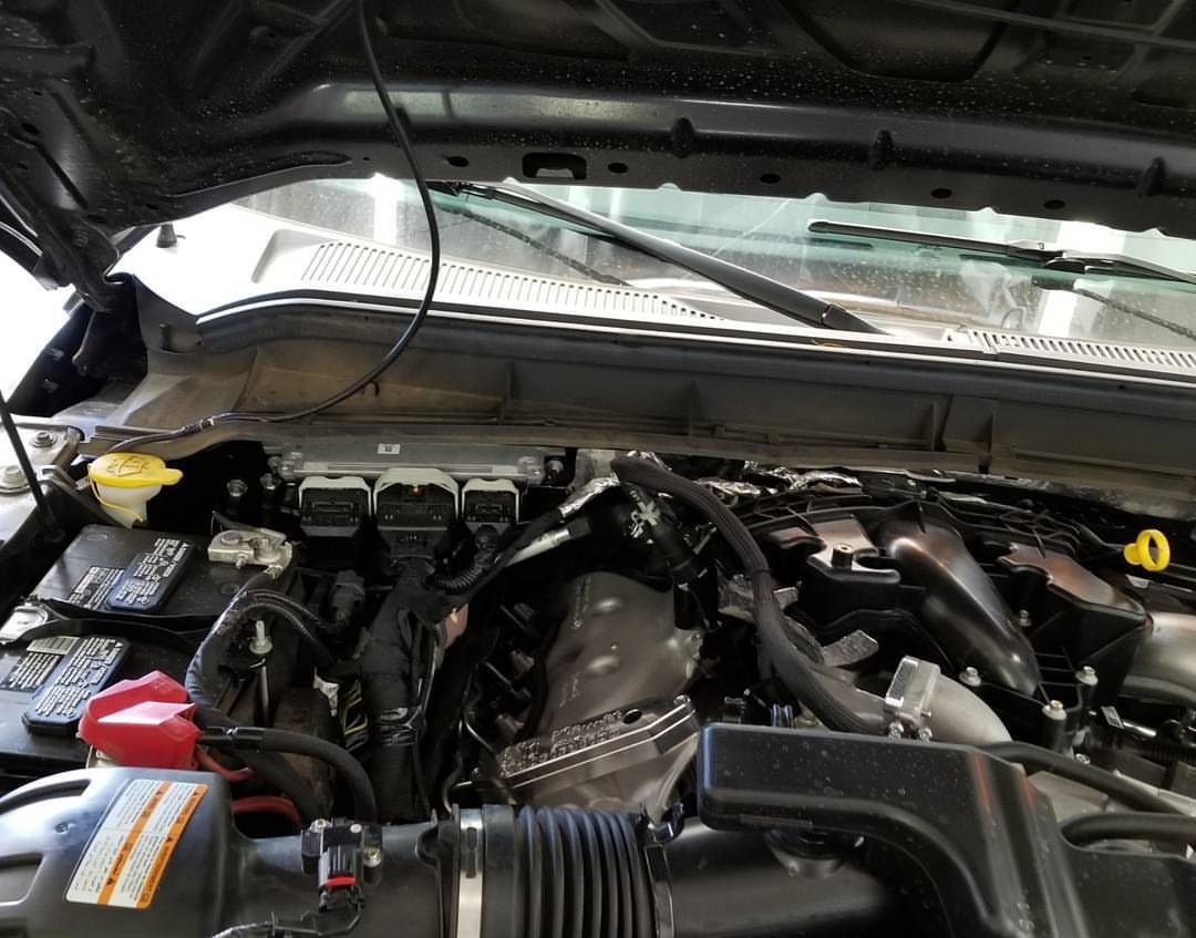 A close up of a car engine with the hood open.