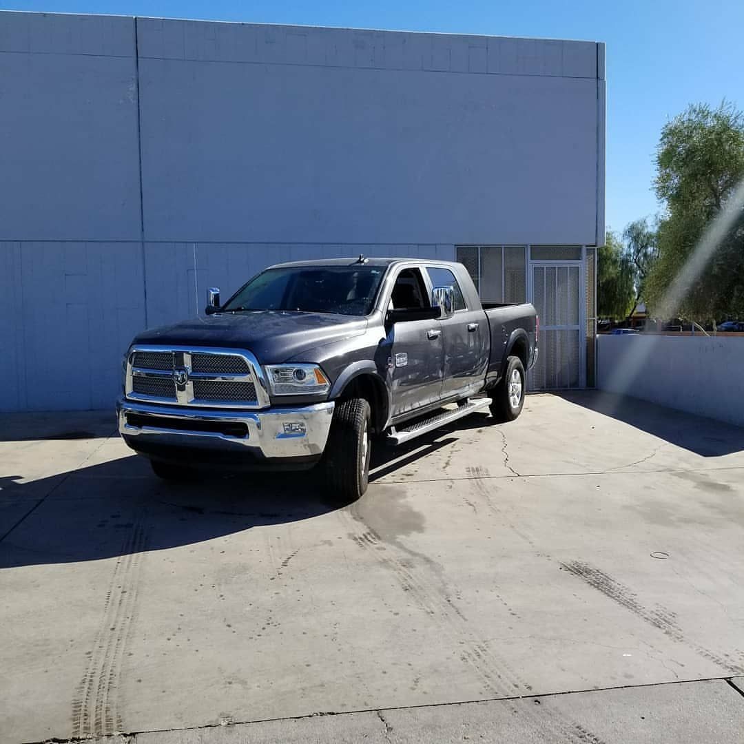 A gray truck is parked in a parking lot in front of a building.
