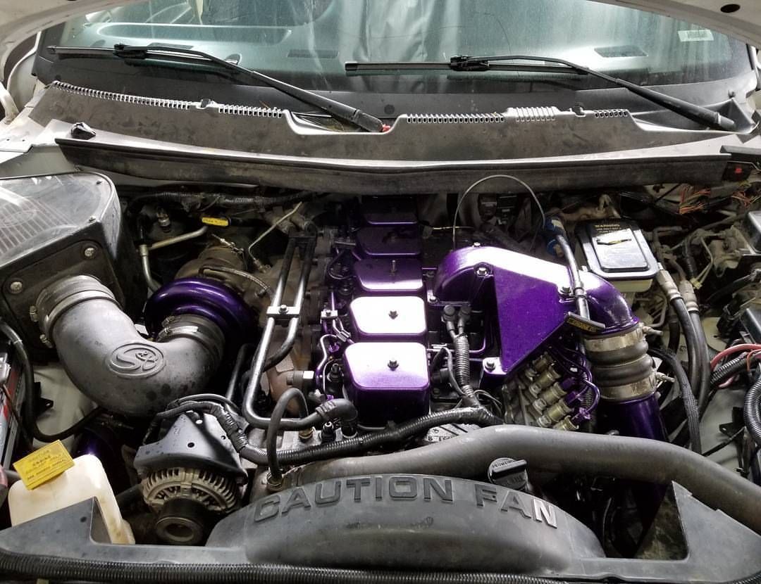 A close up of a car engine with a purple cover that says caution fan