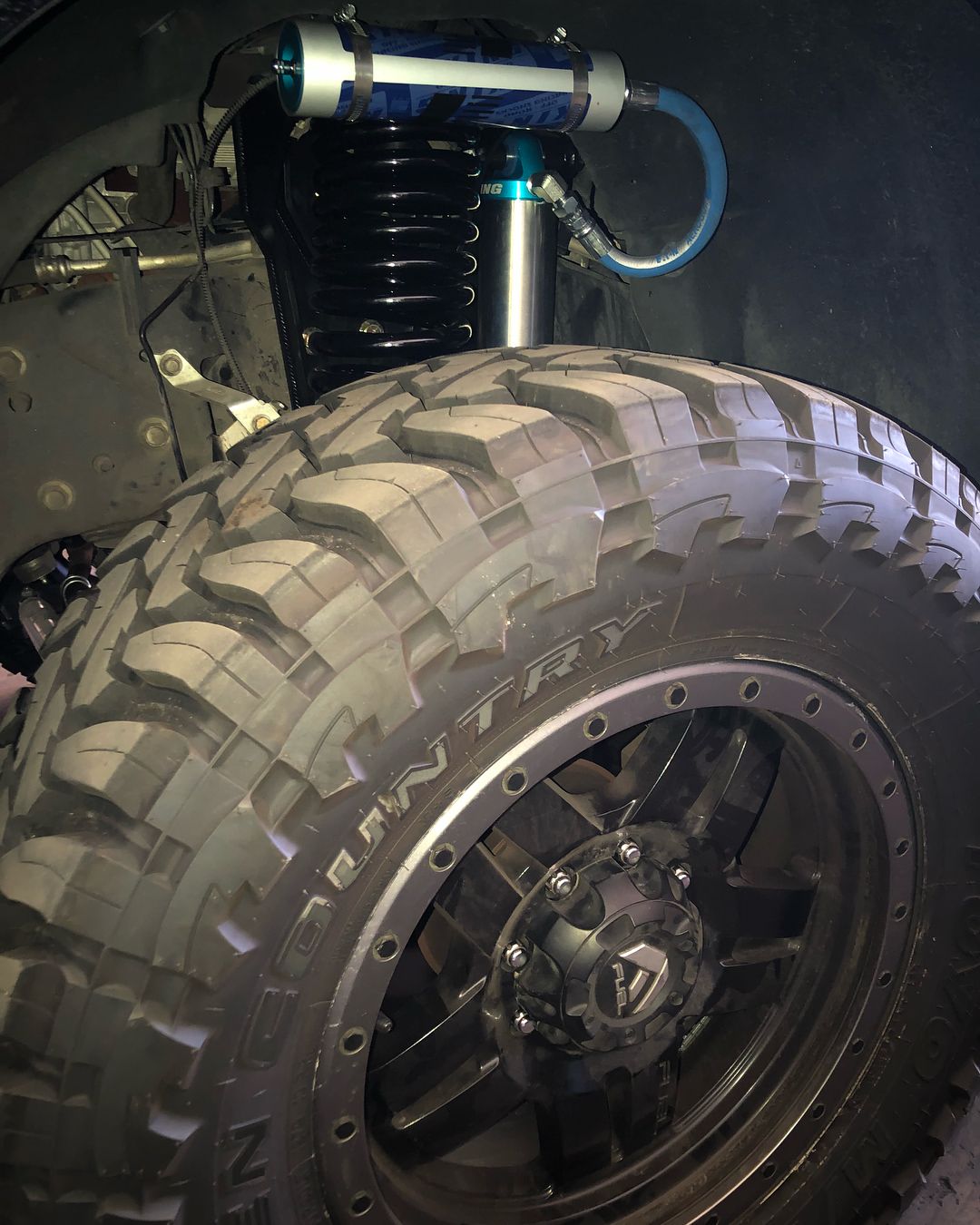 A close up of a tire and shock on a truck