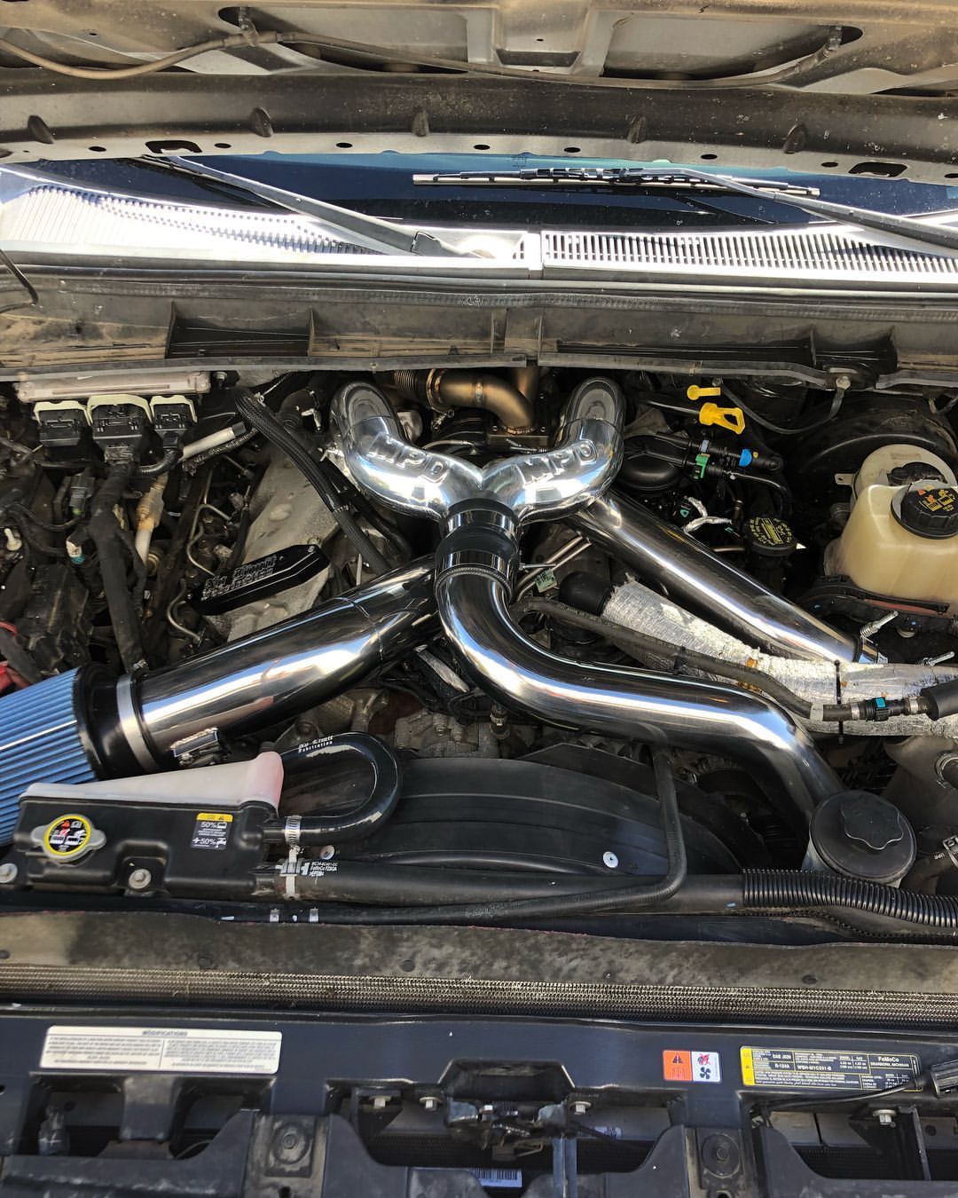 A close up of the engine of a car with the hood open.