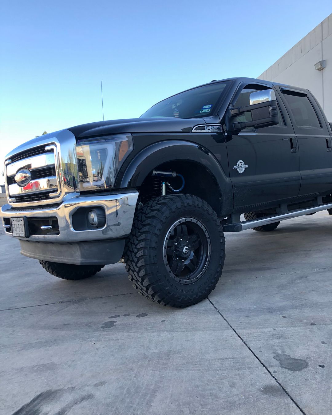 A black ford truck is parked in a parking lot.