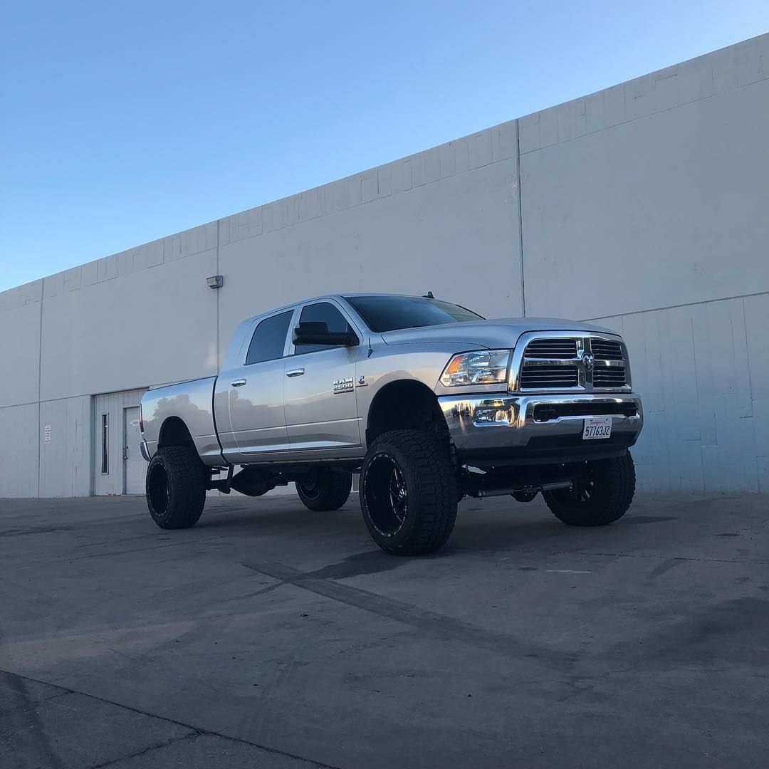 A silver truck is parked in front of a white building.