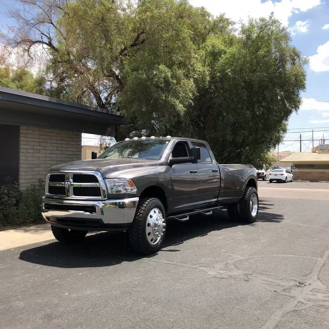 A gray truck is parked on the side of the road in front of a house.