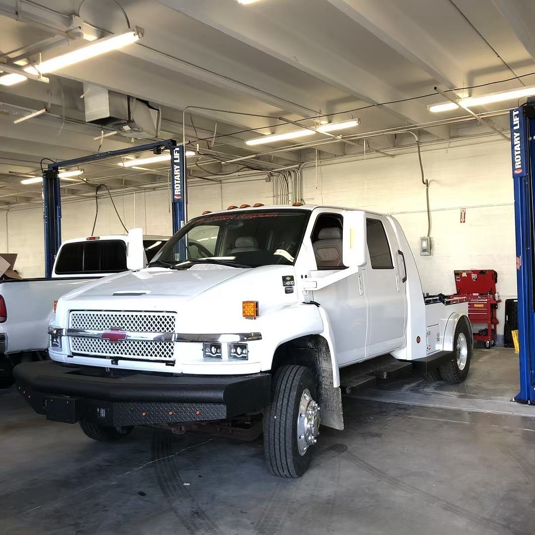 A white truck is parked on a lift in a garage.