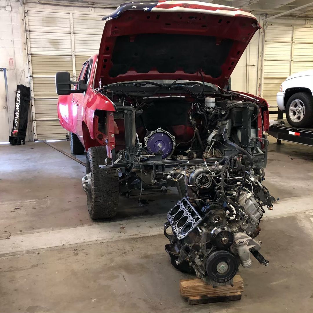 A red truck with the hood up is being worked on in a garage