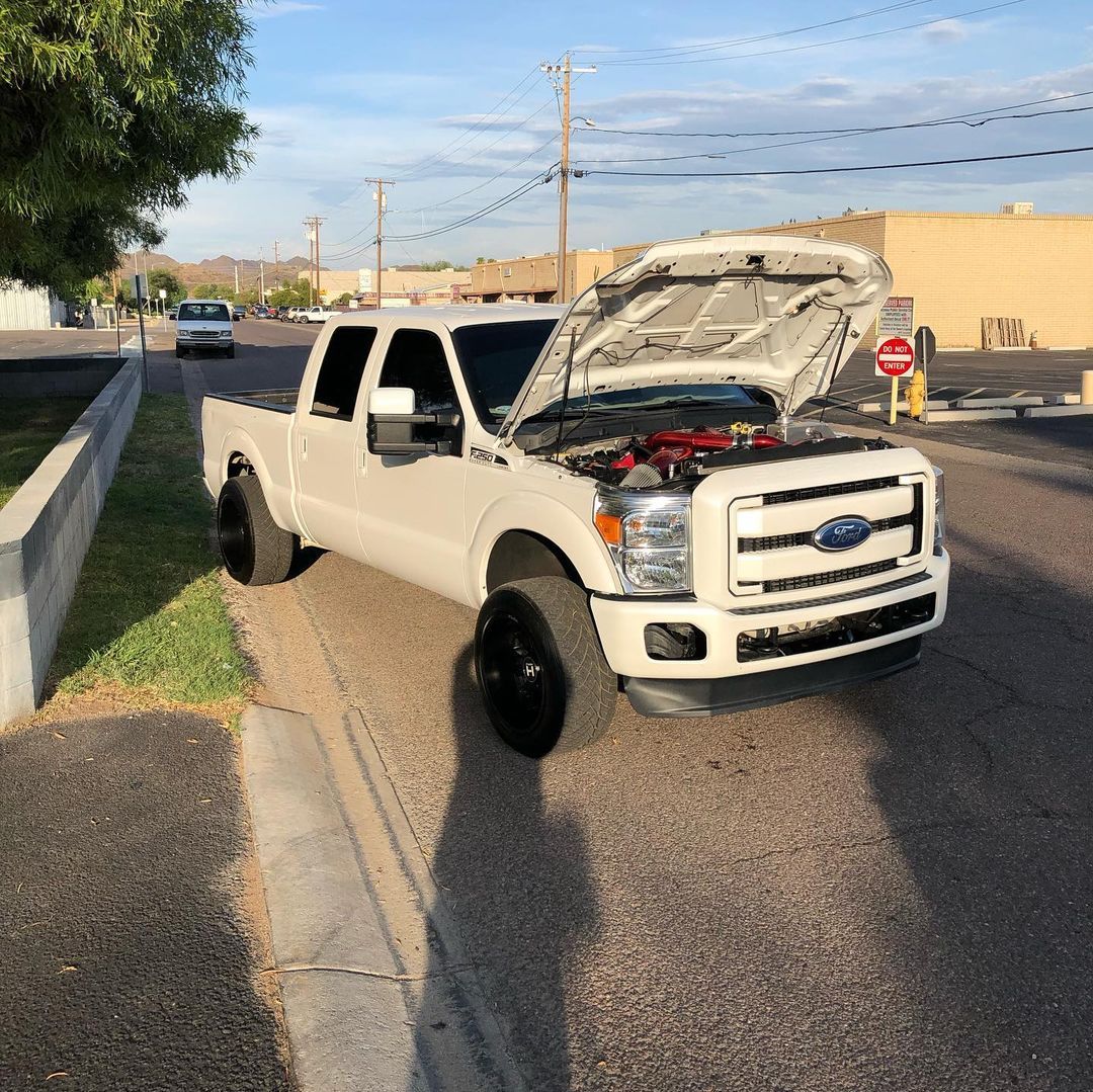 A white truck with the hood up is parked on the side of the road.