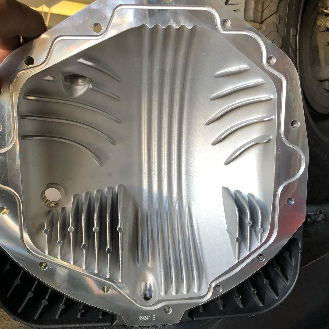 A person is holding an aluminum differential cover in their hand
