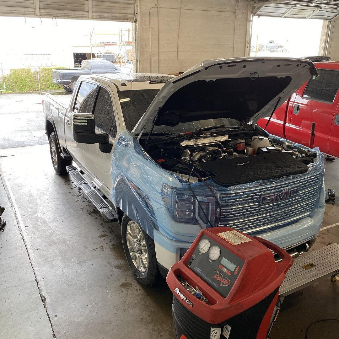 A truck with its hood open is sitting in a garage.