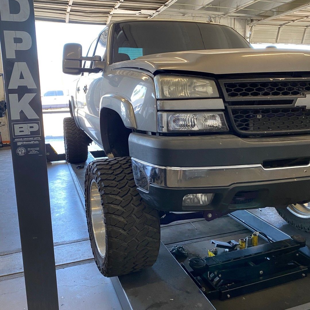 A truck is sitting on a lift in a garage.