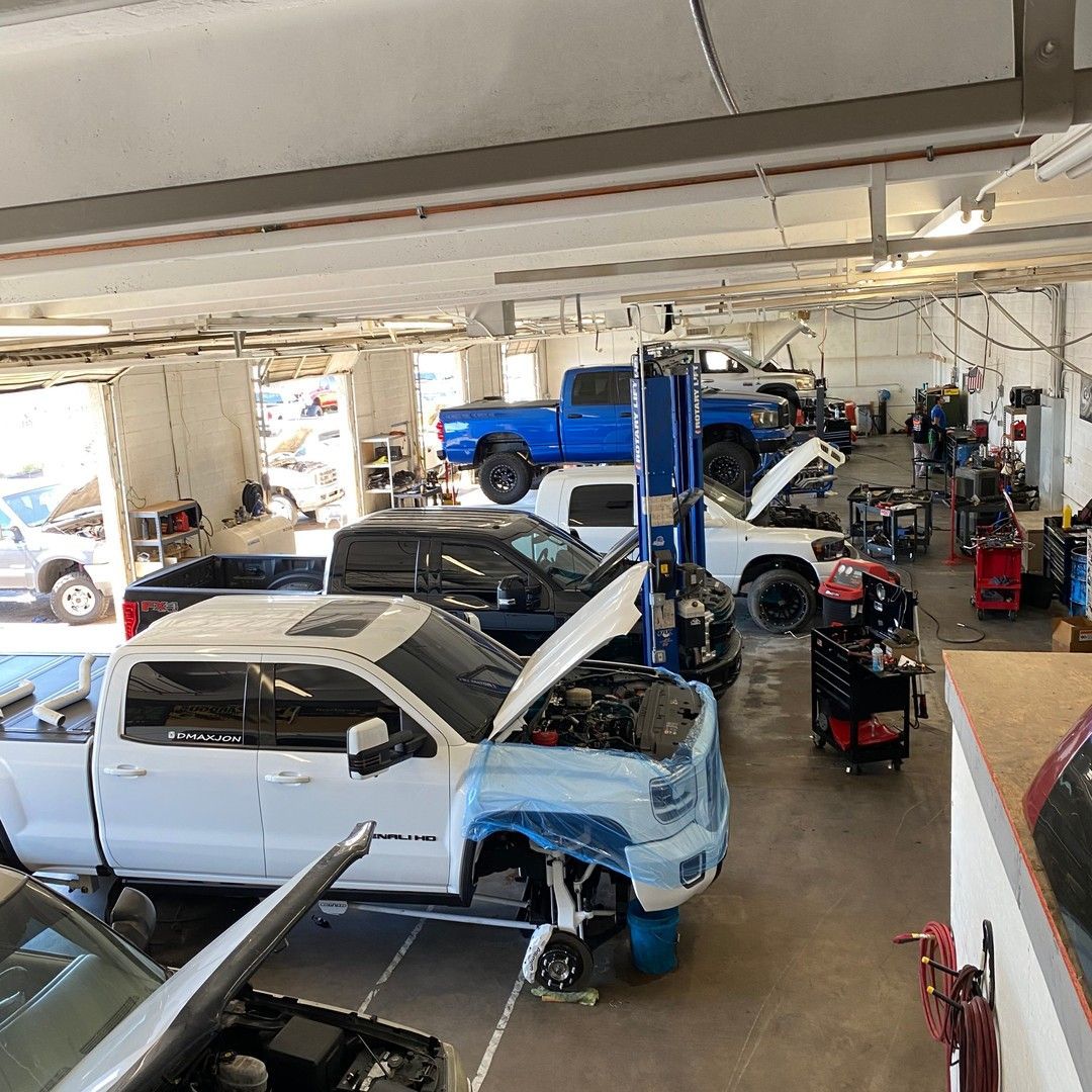 A row of trucks are parked in a garage with their hoods open.