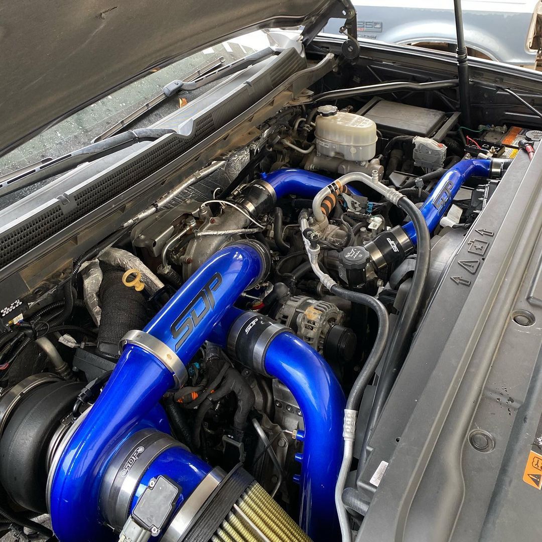 A close up of a car engine with blue hoses and a filter.