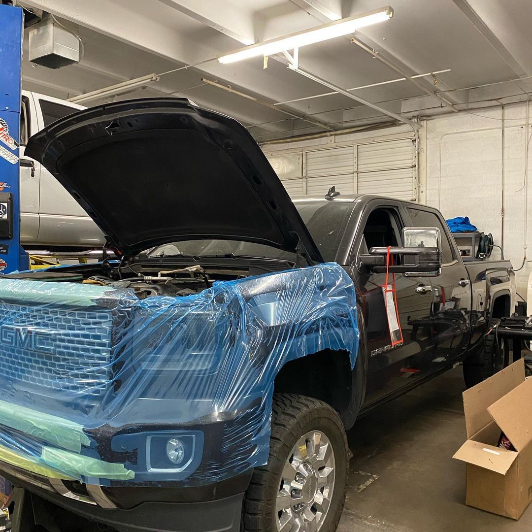 A truck is sitting in a garage with its hood open.