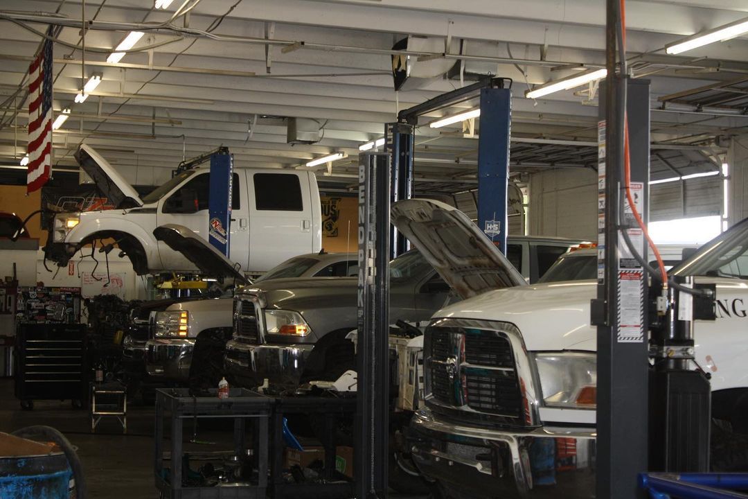 A lot of cars are being worked on in a garage.