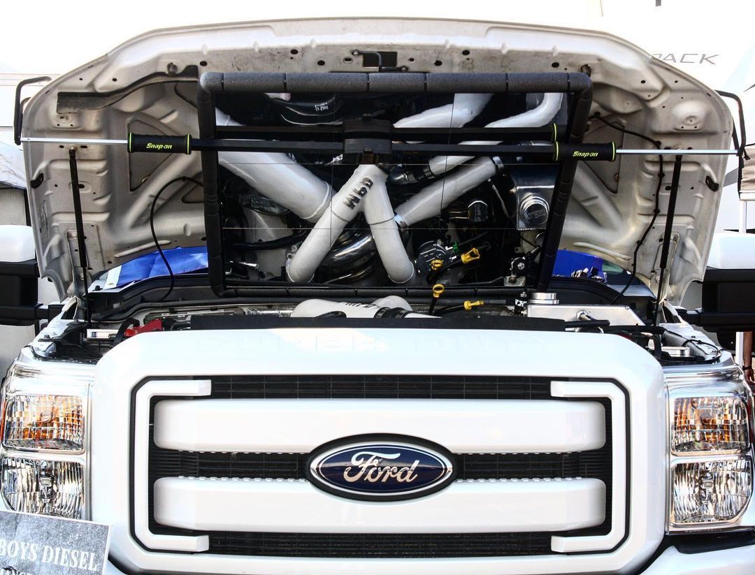 A white ford truck with the hood open