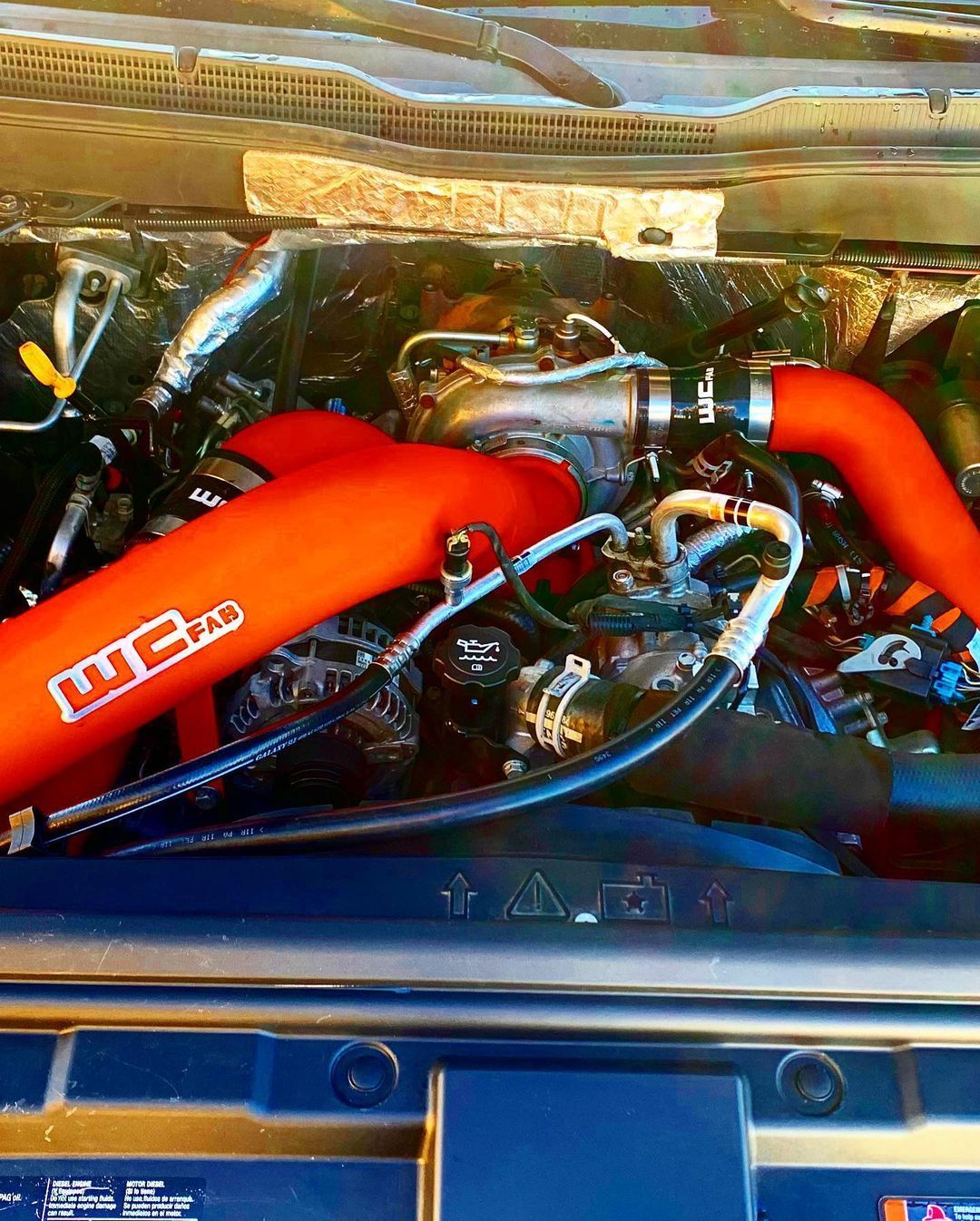 A close up of a car engine with red hose attached to it.
