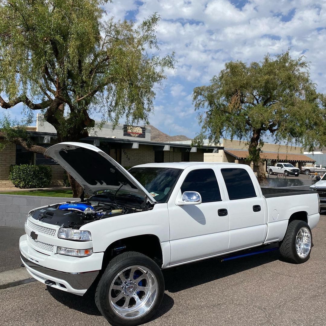 A white truck with the hood up is parked on the side of the road.
