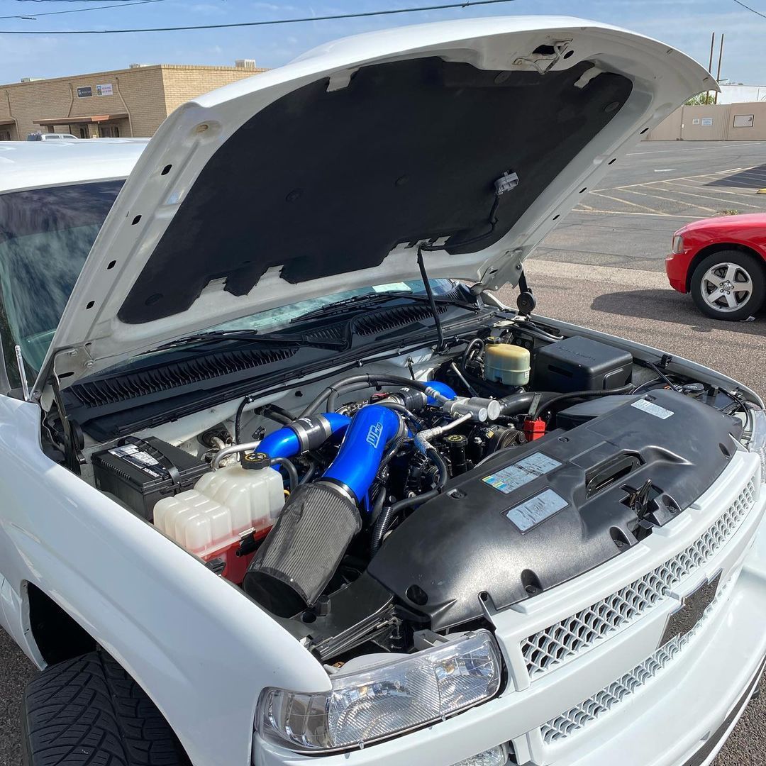 The hood of a white truck is open and the engine is visible.