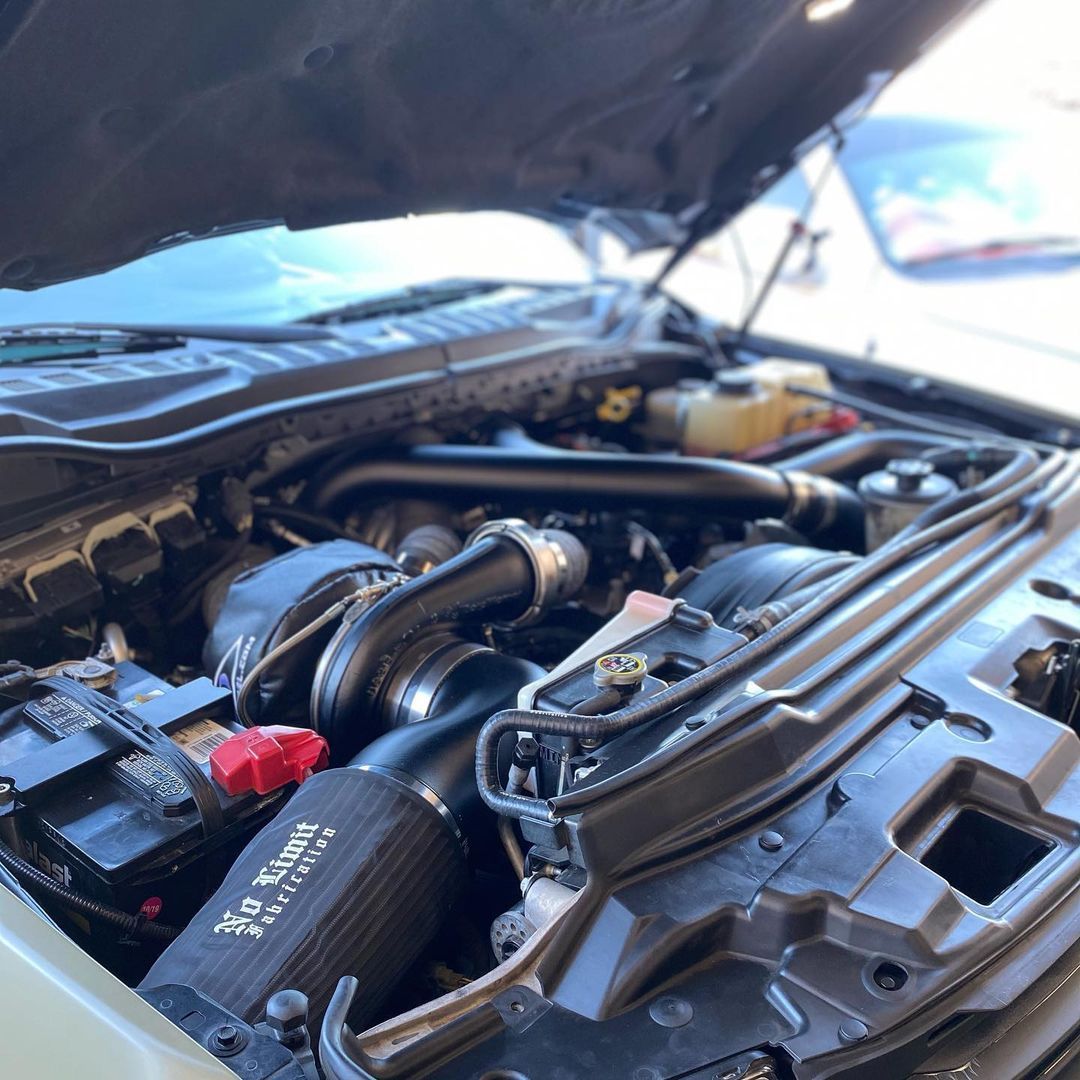 A close up of the engine of a car with the hood open.