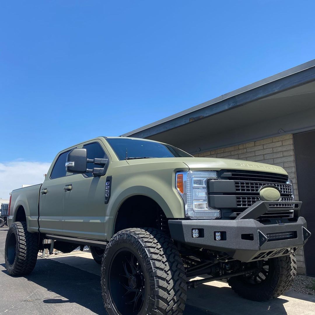A green truck is parked in front of a brick building