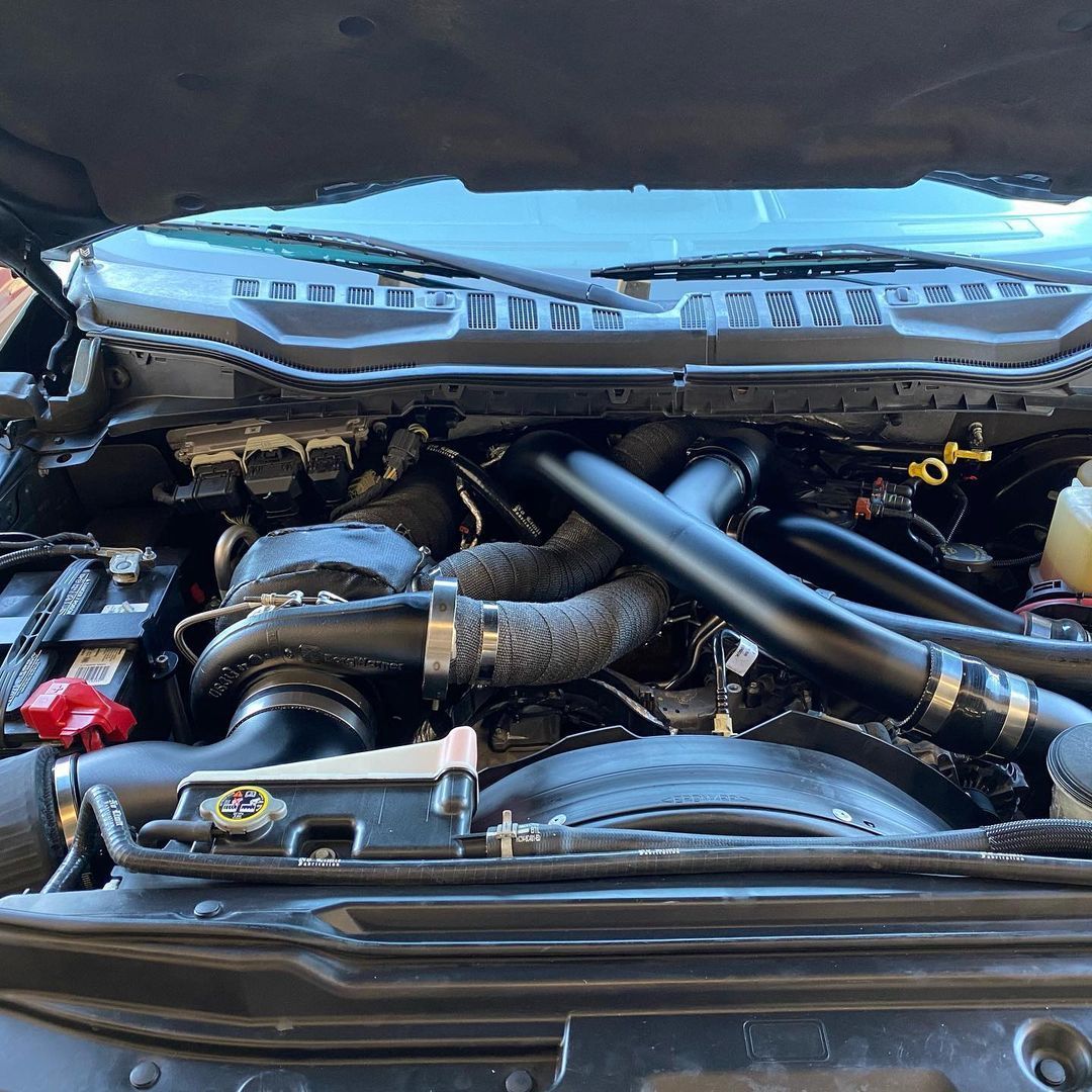 A close up of a car engine with the hood open.