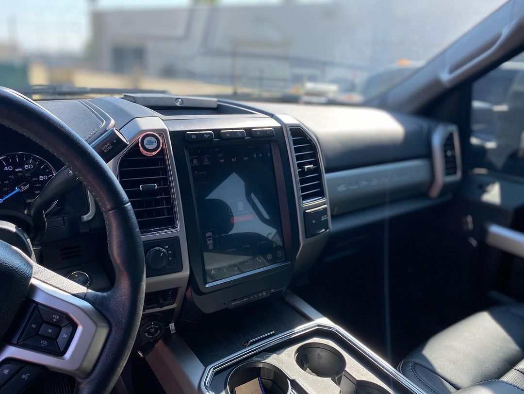 The interior of a car with a steering wheel and a touchscreen display.
