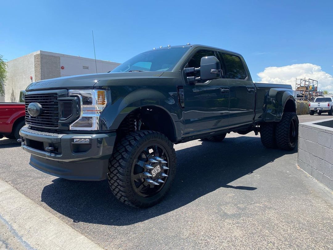 A green ford truck is parked in a parking lot.