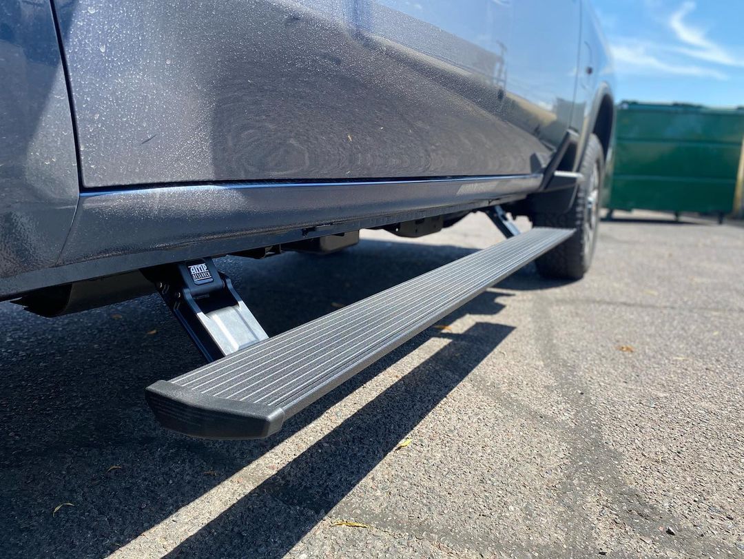 A truck with a side step is parked on the side of the road.