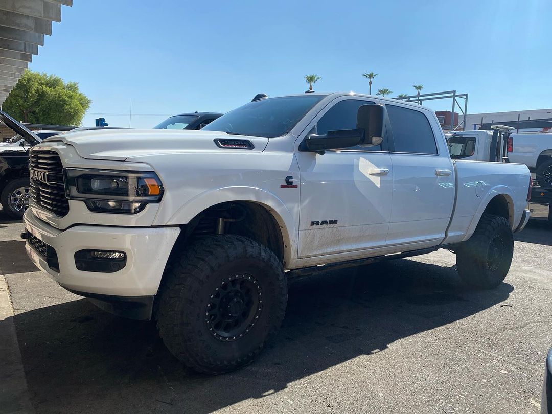 A white ram truck is parked in a parking lot.