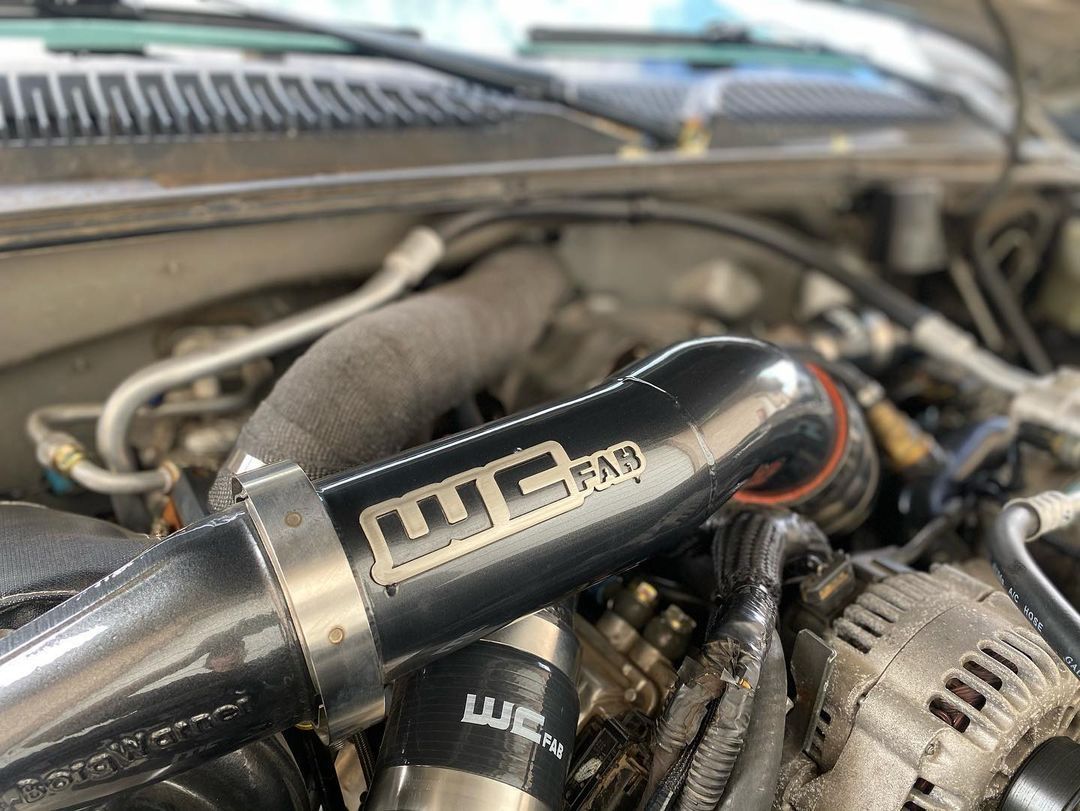 A close up of a car engine with a hose attached to it.