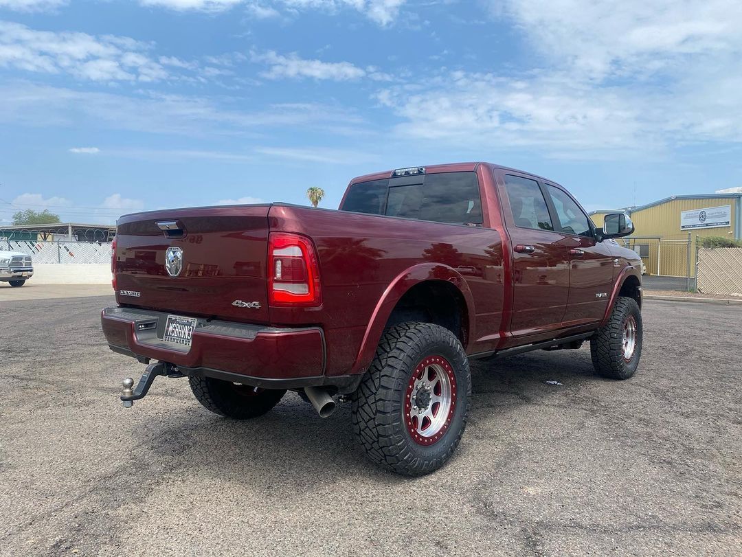 A red ram truck is parked in a gravel lot.