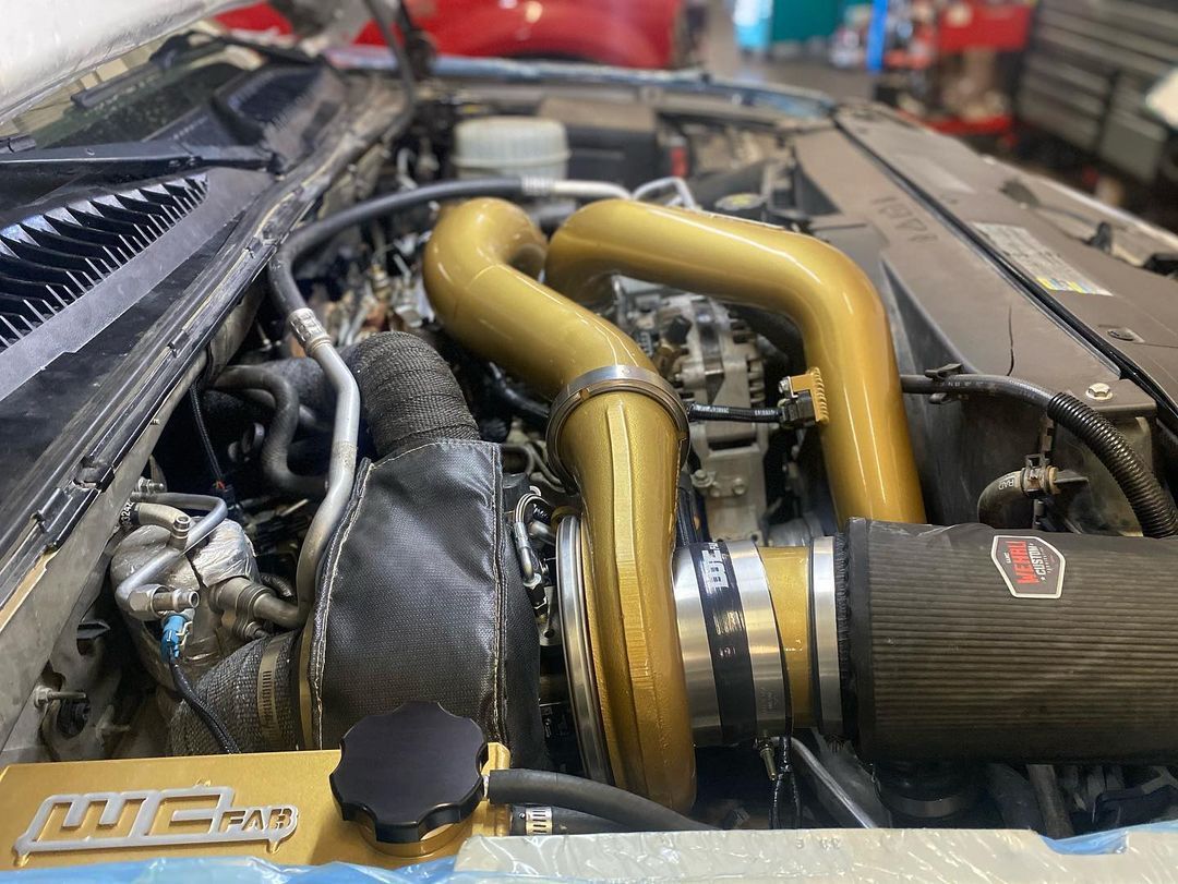 A close up of a car engine with a hood open.