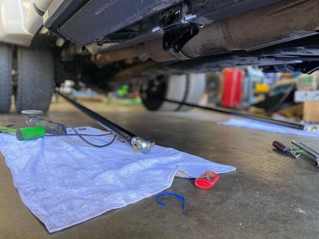 A towel is laying on the ground under a car.