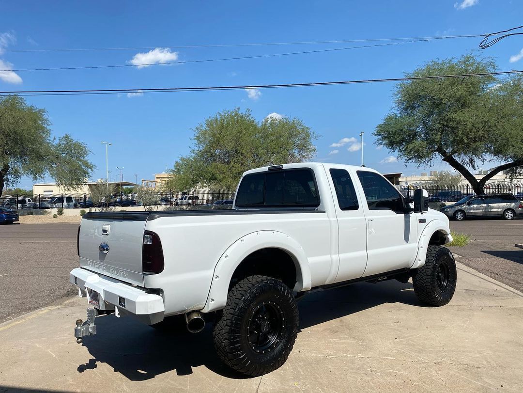 A white truck with black wheels is parked in a parking lot.