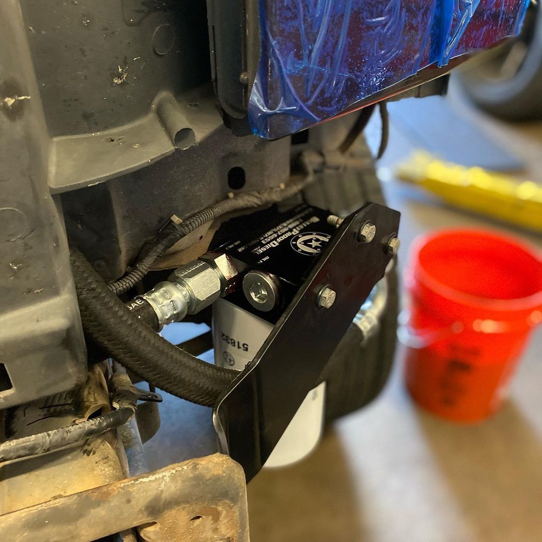 A red bucket is sitting next to a machine that has a filter attached to it