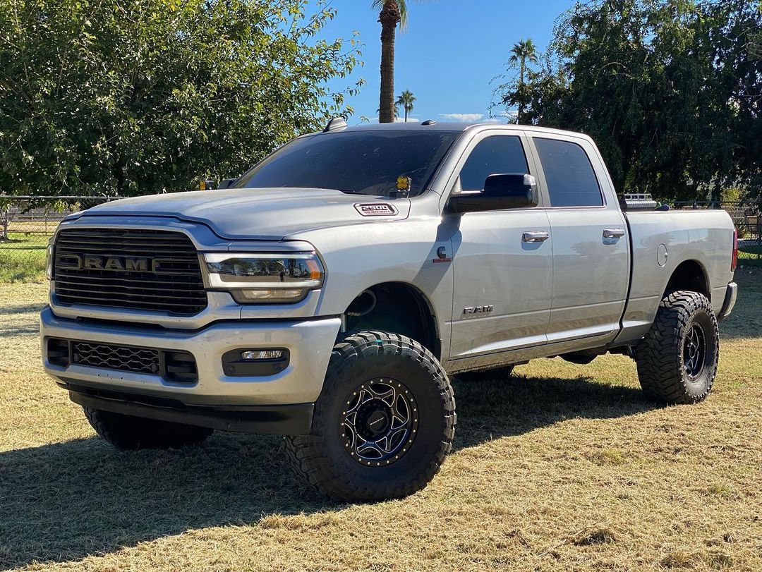A white dodge ram truck is parked in a grassy field.