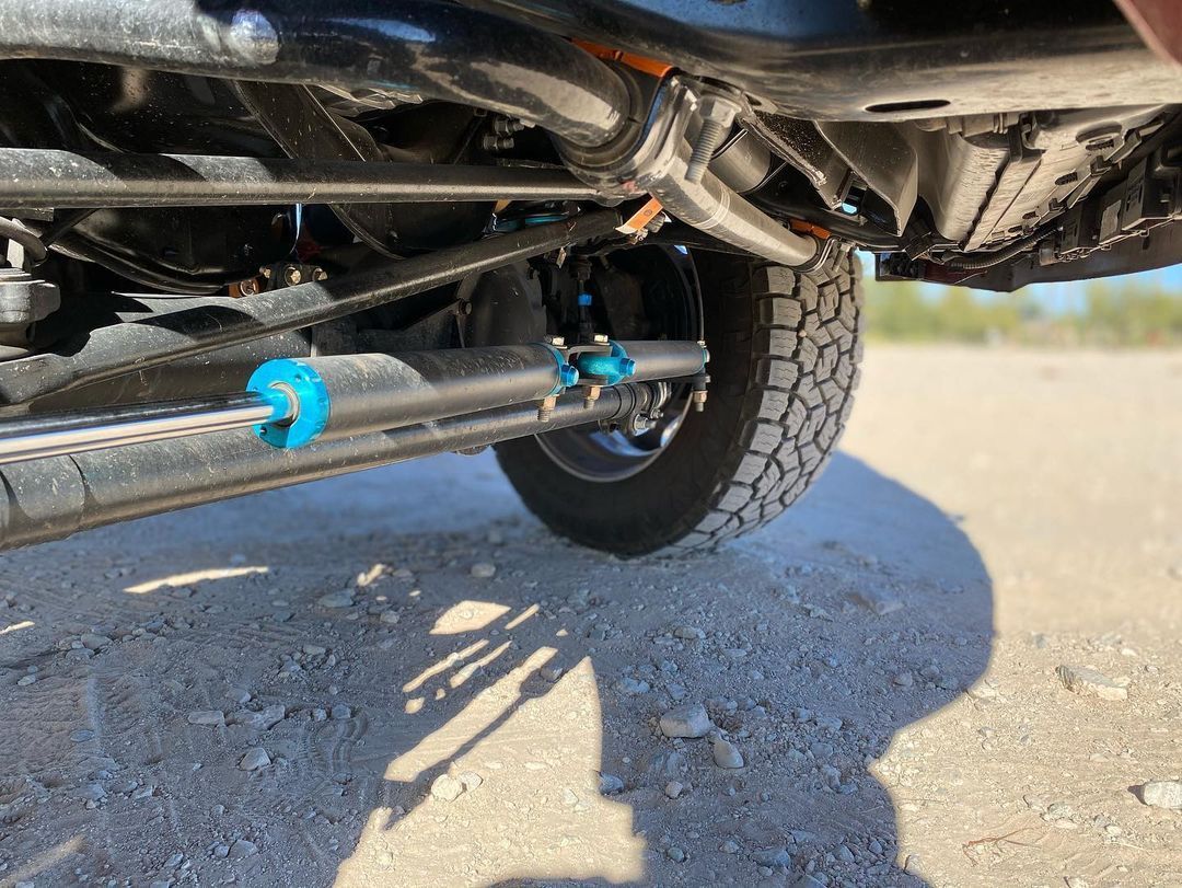 A close up of the underside of a truck on a dirt road.