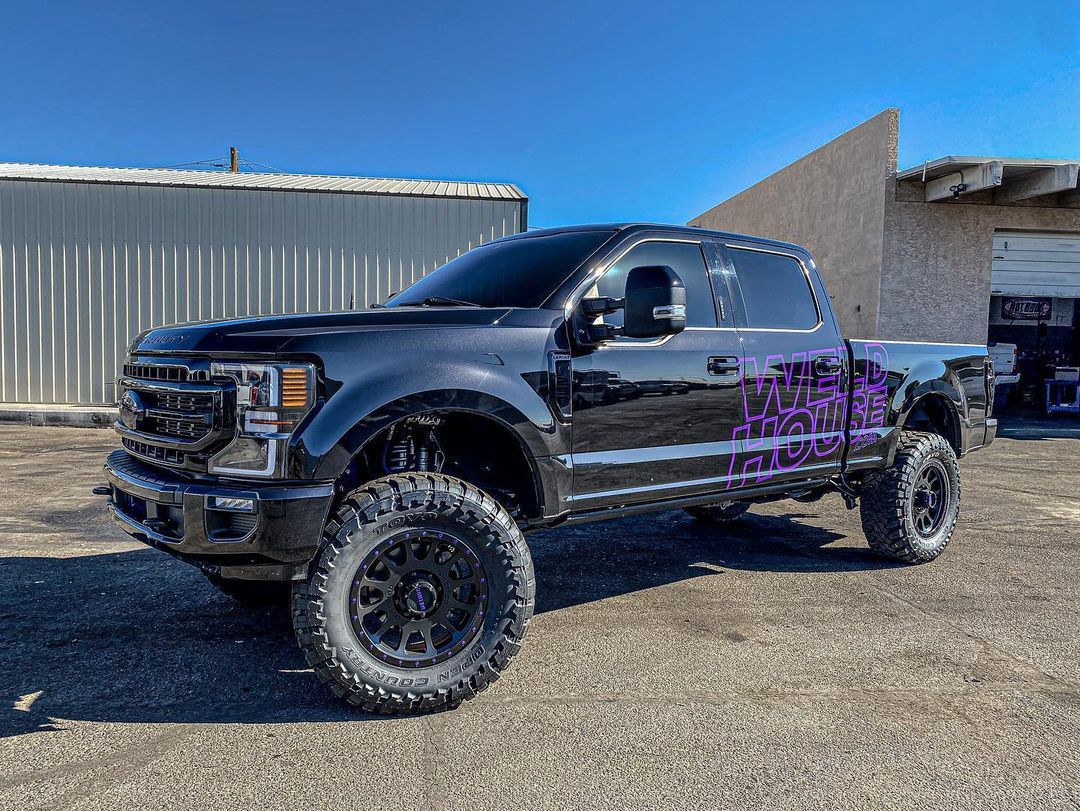 A black truck with purple graphics is parked in front of a building.