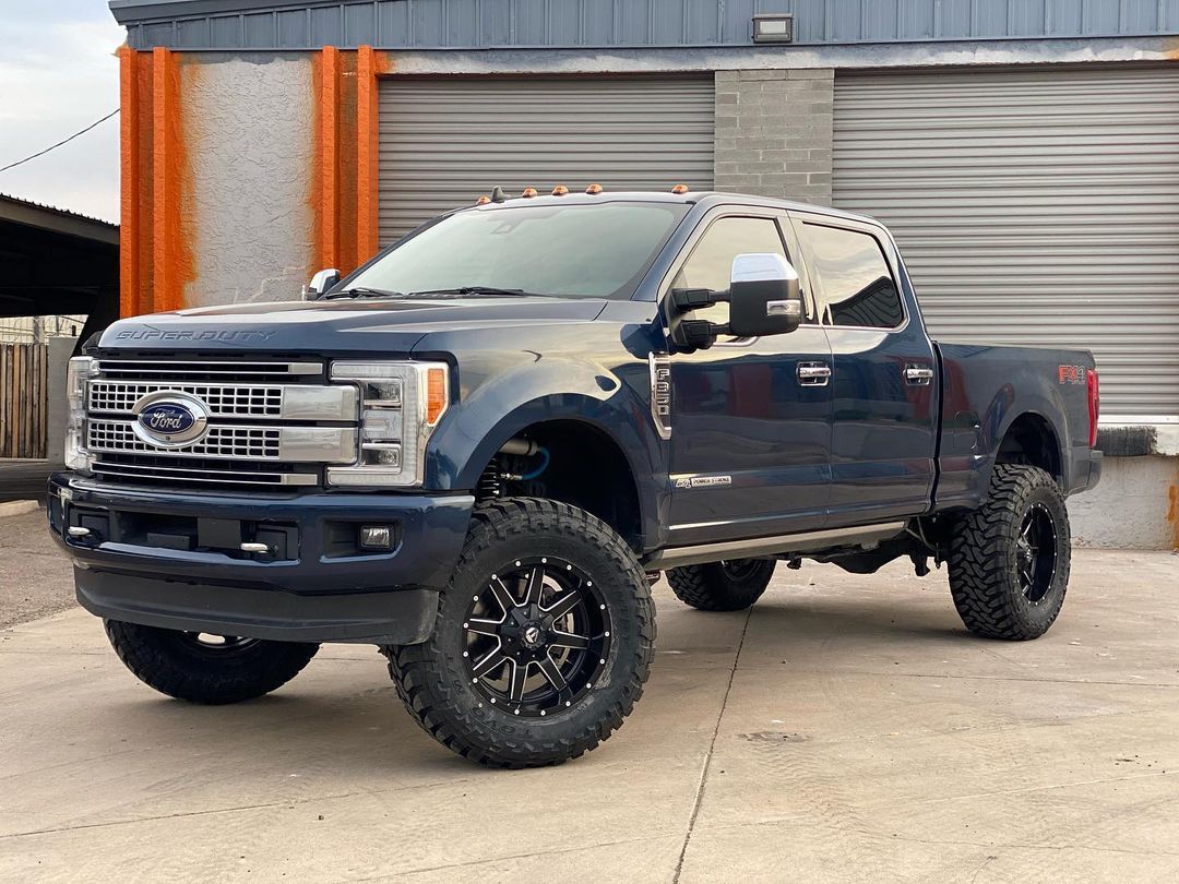 A blue ford f250 pickup truck is parked in front of a building.