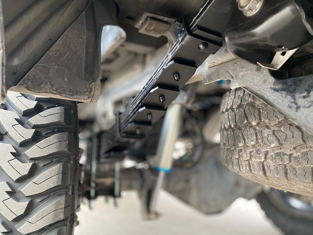 A close up of the underside of a truck with a tire on it.