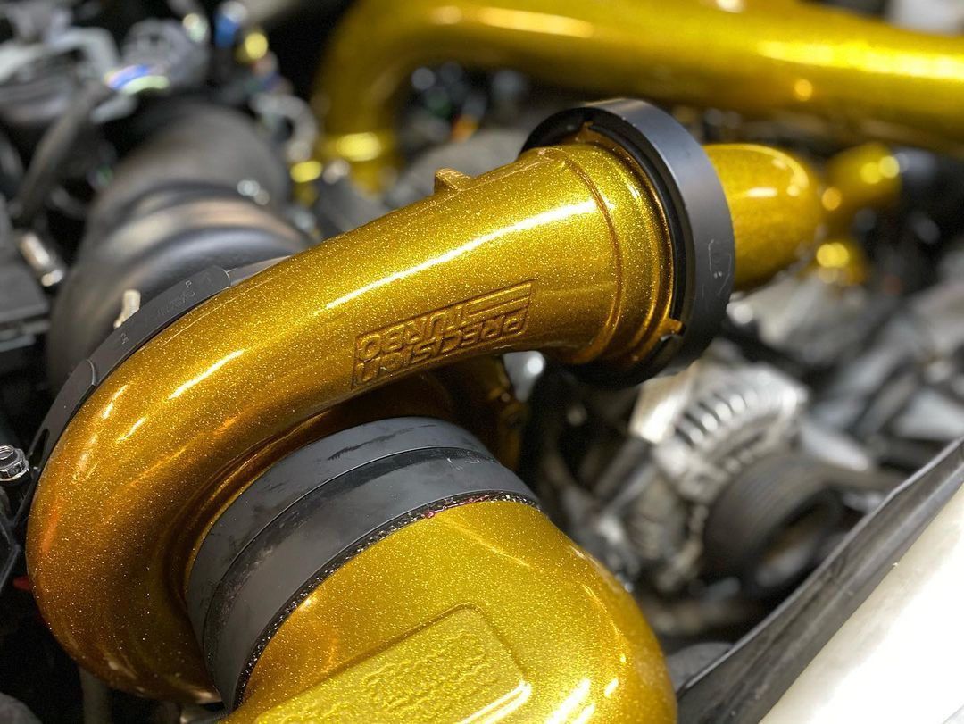 A close up of a gold pipe on a car engine.