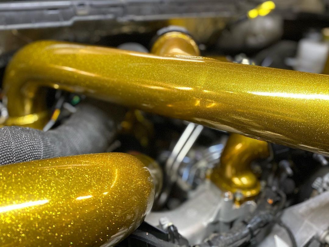 A close up of a gold pipe in a car engine.
