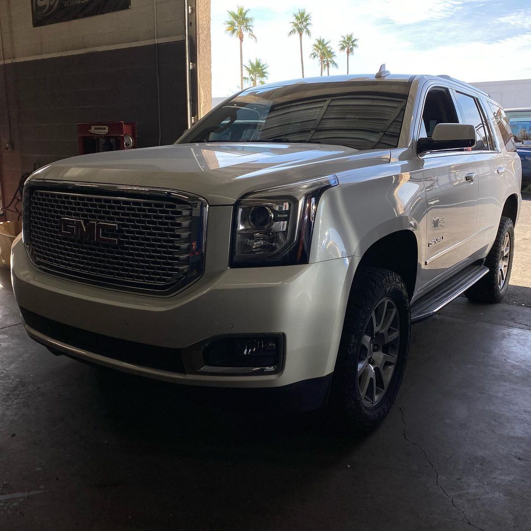 A white gmc yukon is parked in a garage.