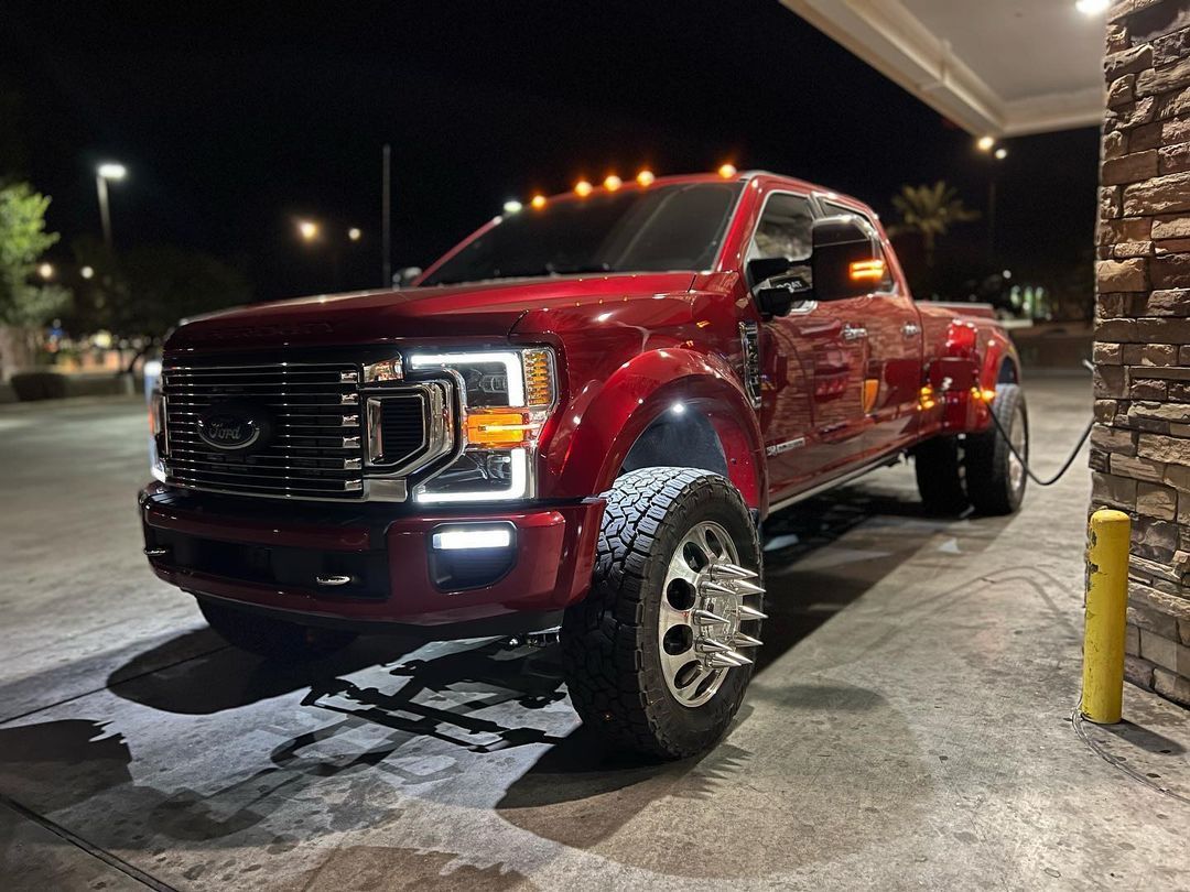 A red truck is parked in a parking lot at night.