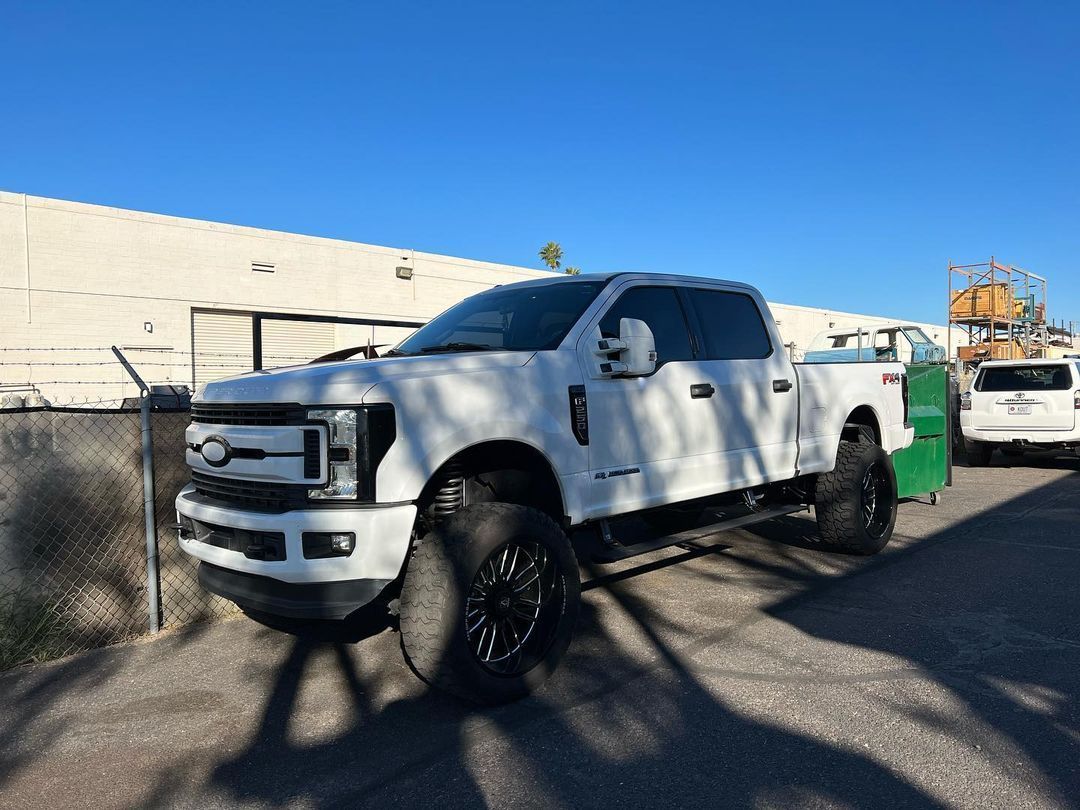 A white truck is parked in a parking lot in front of a building.