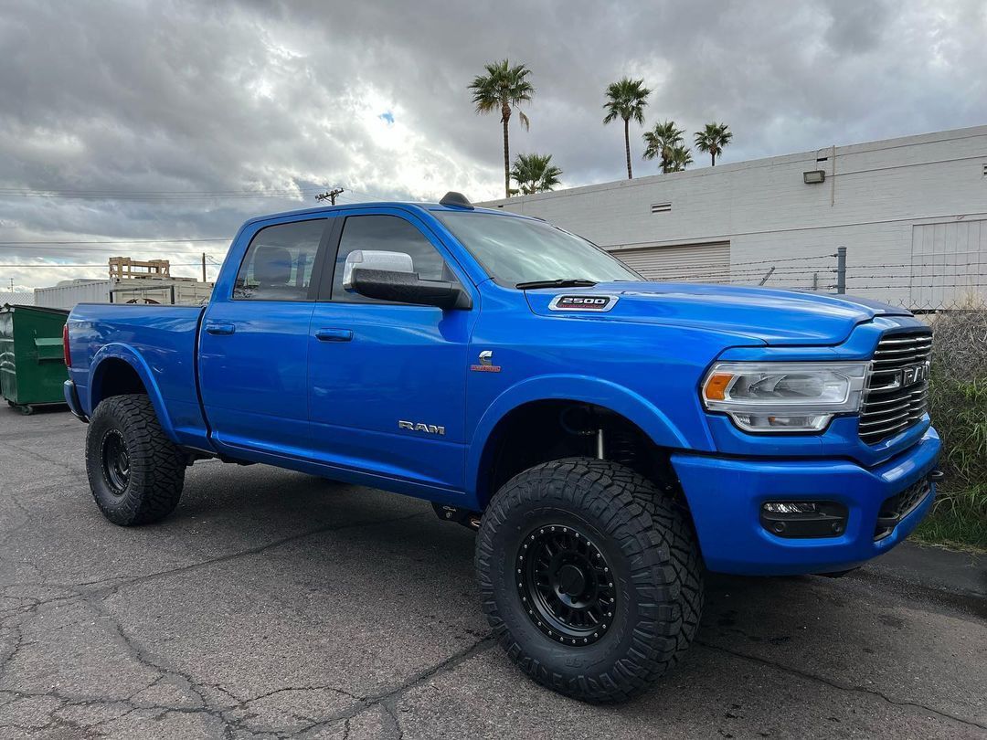 A blue ram truck is parked on the side of the road.