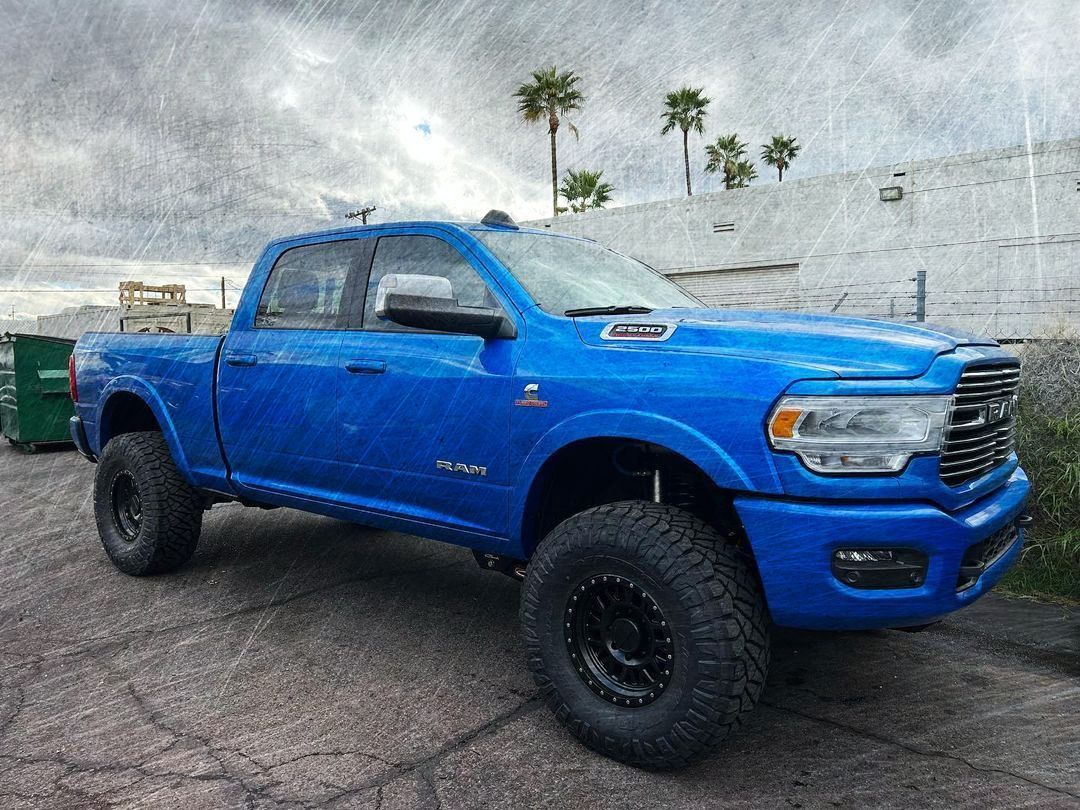 A blue ram truck is parked in a parking lot.