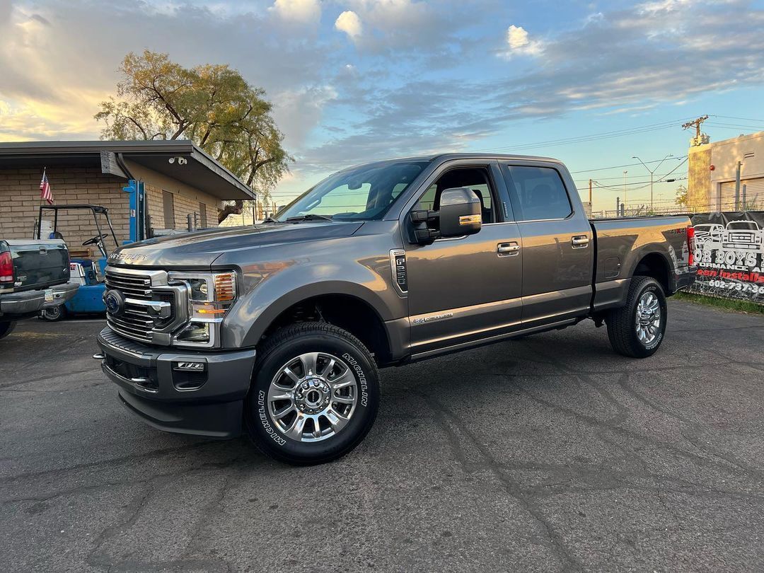 A gray ford truck is parked in a parking lot in front of a building.