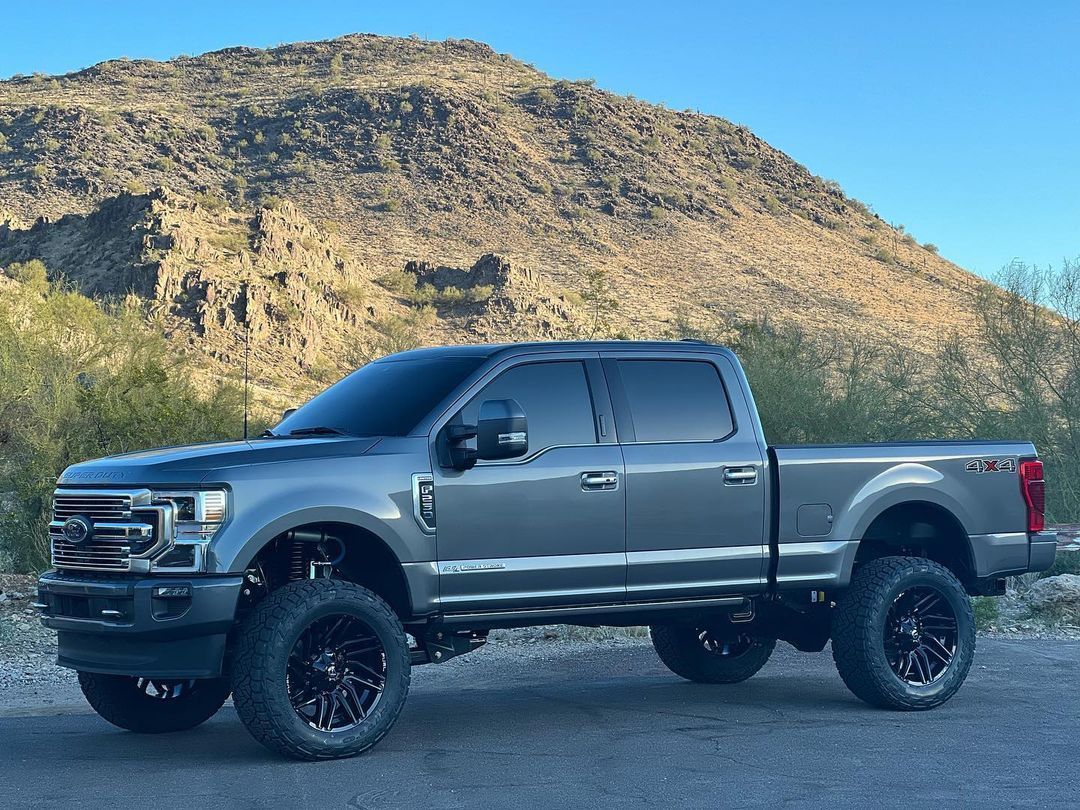 A gray pickup truck is parked in front of a mountain.